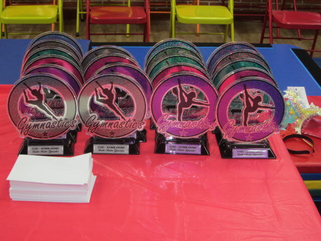 A table of gymnastics trophies and medals ready for Champion Day