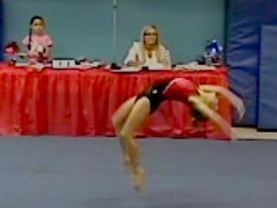 A gymnast fully airborne in the middle of a back handspring