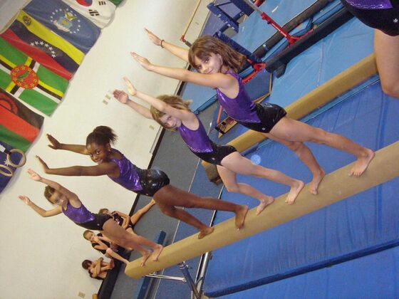 Three gymnasts balancing on the beam with their arms raised