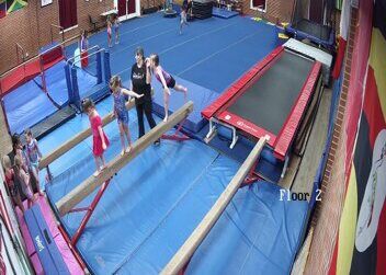 A coach spotting gymnasts on the beam, 2024